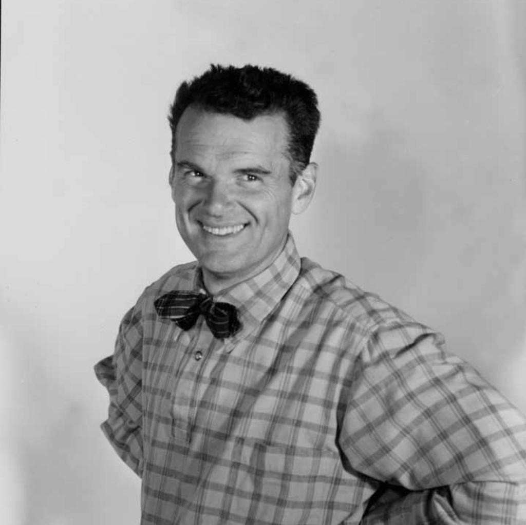 Black and white photo of smiling Charles Eames in bowtie and checked shirt
